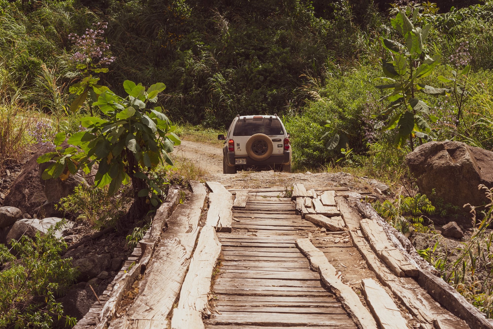 Jeep crossing a plank bridge on the way to the farm